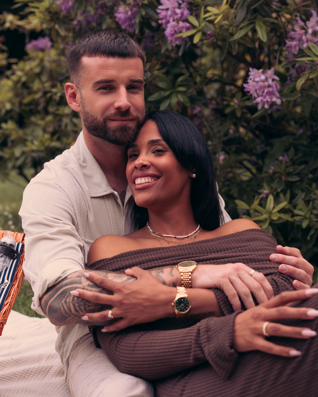 A smiling couple enjoys a sunny moment together. They both wear elegant Balmain gold PVD watches. This captures a sense of timeless style and joyful sophistication.